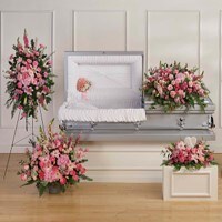 A stunning set of funeral flowers for the family, including a casket piece, casket insert, standing spray, and two floral arrangements all made of serene pink flowers.